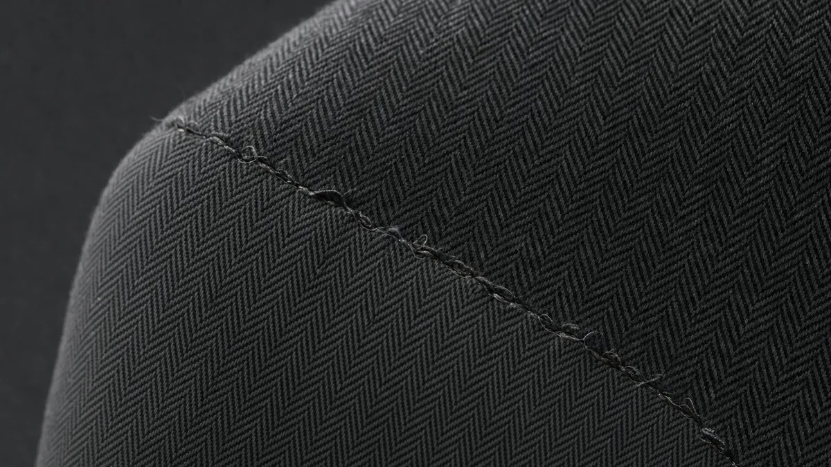 The same detail with typical replica flaws: crooked stitching, glue residue, rough edges